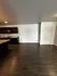 Modern apartment interior featuring sleek wooden flooring, stylish kitchen with dark cabinets, and stainless steel appliances.