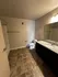 Modern bathroom with sleek granite countertop, elegant tile flooring, and ample lighting.