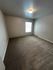 Spacious bedroom with plush carpeting, modern lighting, and a large window for natural light.