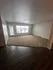 Spacious living room with large window, neutral carpet, and dark wood flooring offering a bright and inviting space.