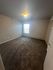 Bright and spacious bedroom featuring plush carpeting and ample natural light through a large window.