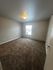 Bright and inviting bedroom with plush carpet and abundant natural light from a large window.