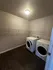 Spacious and modern laundry room with energy-efficient washer and dryer set, featuring sleek wooden flooring and ample shelving.