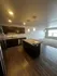 Modern kitchen with stylish dark wood cabinets, granite island, and warm lighting in an open-concept apartment.