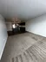 Modern open-plan apartment with a spacious living area, plush carpeting, and a sleek kitchen with stainless steel appliances.
