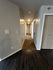 Inviting apartment hallway with modern wood and carpet flooring, softly lit by ceiling lights for a cozy ambiance.