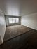 Bright living room with large window, cozy carpeted area, and sleek wood flooring.