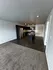 Modern open-plan kitchen with sleek appliances, dark cabinetry, and cozy living area with plush carpeting and stylish lighting.