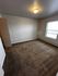 Bright and spacious bedroom with plush carpeting and natural light from a large window.