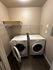 Modern laundry room with sleek appliances, featuring a stacked washer and dryer, and efficient shelving.