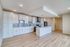 Sleek modern kitchen with white cabinetry, stainless steel appliances, and stylish pendant lighting on a warm wood floor.