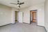 Bright, modern bedroom with sleek ceiling fan and open doorways leading to additional rooms, featuring soft carpeting and neutral tones.