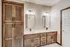Elegant bathroom showcasing double sink vanity with warm wooden cabinetry and stylish lighting fixtures.