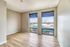 Bright, modern room with floor-to-ceiling windows, offering stunning city views and sleek hardwood flooring.