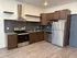 Modern kitchen with stainless steel appliances, dark wood cabinets, and sleek tile backsplash.
