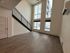 Bright open-concept living area with high ceilings and expansive windows, featuring sleek modern staircase and elegant flooring.