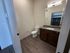 Modern bathroom featuring sleek wooden flooring, a stylish vanity with a granite countertop, and a large mirror enhancing space.