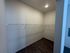 Spacious walk-in closet with sleek wooden flooring and ample shelving, perfect for organized storage.