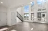 Bright and airy living space with large windows and modern staircase, offering a view of the cityscape.