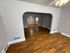 Elegant room with polished hardwood floors, neutral gray walls, and stylish archways offering a spacious, open-concept layout.