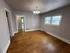 Bright room with wooden floors, modern chandelier, and large windows, perfect for versatile living space.