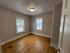 Bright room with polished wooden floors and two windows offering natural light, ideal for a cozy bedroom or home office.