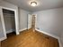 Bright and spacious room with polished hardwood floors, white trim, and built-in closet. Ideal for a cozy bedroom or home office space.