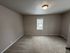 Spacious room with soft carpet, neutral walls, and a bright window offering natural light.