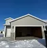 Charming single-story home with a spacious garage, set against a crisp blue sky and surrounded by fresh winter snow.
