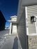 Modern entrance of a snow-covered house with gray siding and bold address numbering, showcasing elegant exterior lighting.