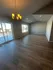Bright and airy living space with elegant chandelier, large windows, and beautiful wooden flooring overlooking a spacious outdoor deck.