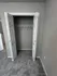Modern apartment closet with double doors, fresh gray walls, and soft carpet flooring.