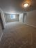Spacious room with plush carpeting and ample natural light, perfect for a cozy living area.