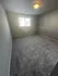 Cozy bedroom with plush carpet, soft natural lighting, and a modern ceiling light fixture.