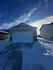 Charming single-story home with a two-car garage, set against a stunning winter sky.