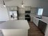 Modern kitchen with sleek white cabinets, stainless steel appliances, and elegant pendant lighting over a spacious countertop.