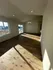 Bright and airy room with elegant wooden flooring, modern recessed lighting, and large windows offering natural light.