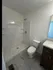 Modern bathroom featuring a sleek shower, elegant marble tile floor, and compact vanity for efficient use of space.