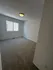 Bright, spacious bedroom with soft carpeting, large window, and modern light fixture.