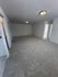 Spacious living area with plush gray carpeting and modern recessed lighting, leading to bright adjoining rooms.