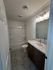 Modern bathroom with elegant marble countertop, sleek vanity mirror, and spacious bathtub.