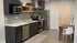 Modern kitchen featuring sleek dark cabinetry, stainless steel appliances, and a cozy dining area with stylish decor.