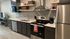 Modern kitchen with sleek stainless steel appliances, elegant dark cabinetry, and open shelving for a contemporary look.