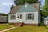 Charming single-story home with blue siding, inviting front steps, and a well-kept lawn, perfect for cozy living.