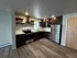 Modern kitchen with sleek dark wood cabinets, stainless steel appliances, and stylish open shelving.