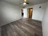 Bright and airy room with modern wood flooring, ceiling fan, and open doorway leading to kitchen with contemporary design.
