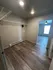 Modern apartment showcasing a spacious walk-in closet with sleek wooden flooring and ample overhead shelving, leading to a brightly lit room.