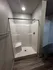 Modern apartment bathroom featuring a sleek shower with built-in seating and contemporary lighting.