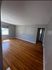 Spacious, sunlit living room featuring beautiful hardwood flooring and freshly painted walls, perfect for a cozy and inviting atmosphere.