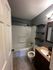Modern bathroom featuring elegant fixtures, a full bathtub, and stylish shelving on serene tiled flooring.